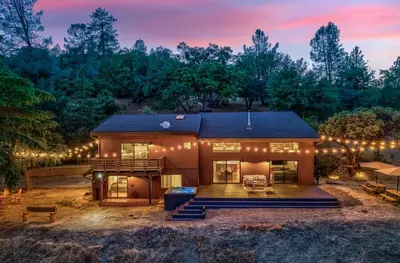 a house with lights on the side of it at Yosemite Sunrise House with hot tub/views/game room in Oakhurst