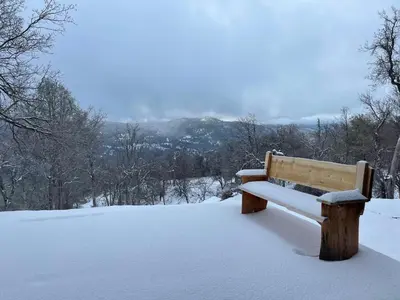 a wooden bench covered in snow in a park at Yosemite Sunrise House with hot tub/views/game room in Oakhurst