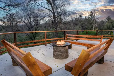 two benches sitting on a deck with a fire pit at Sunset Retreat- TWO houses with hot tub, firepit, multiple kitchens, sleeps 20 in Coarsegold
