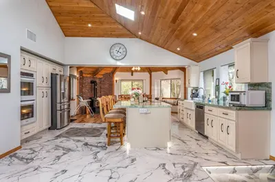 a kitchen with a marble floor and a clock on the wall at Sunset Retreat- TWO houses with hot tub, firepit, multiple kitchens, sleeps 20 in Coarsegold