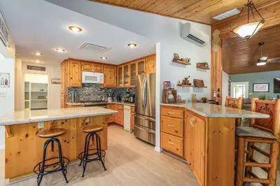 a kitchen with wooden cabinets and a large island with bar stools at Yosemite Creekside Retreat with spa/games/EV Charger and more in Oakhurst