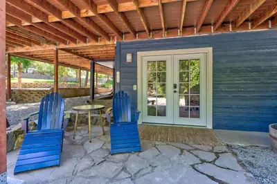 a patio with two blue chairs and a table at Yosemite Creekside Retreat with spa/games/EV Charger and more in Oakhurst