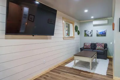 a living room with a large flat screen tv on the wall at Yosemite Creekside Retreat with spa/games/EV Charger and more in Oakhurst