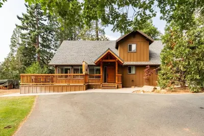 a large wooden house with a large deck at Sequoia Retreat- Spacious Cabin, Hot tub, & Sundeck in Ponderosa