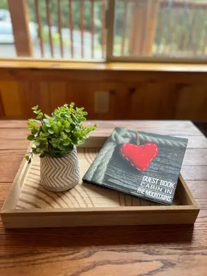 a book and a vase with a plant on a table at Sequoia Retreat- Spacious Cabin, Hot tub, & Sundeck in Ponderosa