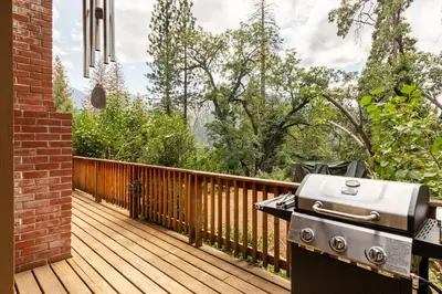 a grill on the deck of a house at Sequoia Retreat- Spacious Cabin, Hot tub, & Sundeck in Ponderosa