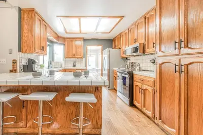 a large kitchen with wooden cabinets and white appliances at Stylish 3BR/2BA Retreat w/ Pool! Dream Getaway in Fresno