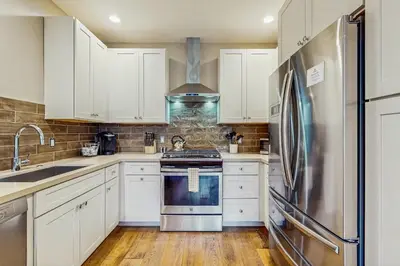 a kitchen with white cabinets and a stainless steel refrigerator at Red Mountain Lodge in Truckee