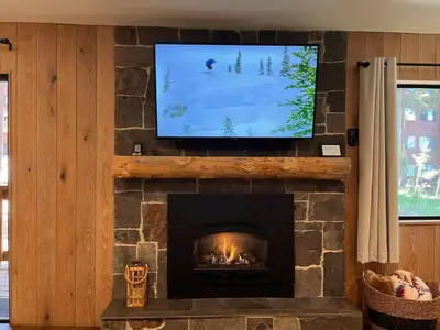 a living room with a fireplace with a flat screen tv at Cozy Ski Condo - Walk to Canyon - Dog Friendly in Mammoth Lakes