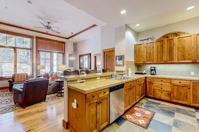 a kitchen with wooden cabinets and a living room at Snowscape Serenity in Truckee