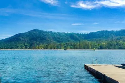 a dock on a lake with a mountain in the background at Bass Lake Lodge in Bass Lake