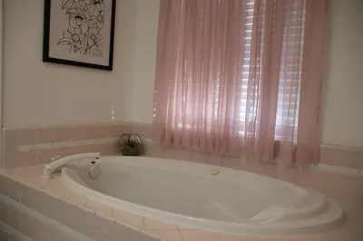 a large tub in a bathroom with a pink curtain at Casa Mariposa - A Foothill Retreat near Yosemite in Mariposa