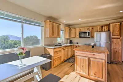 a kitchen with wooden cabinets and a large window at Oakhurst Duplex about 13 Mi to Yosemite National Park! in Oakhurst