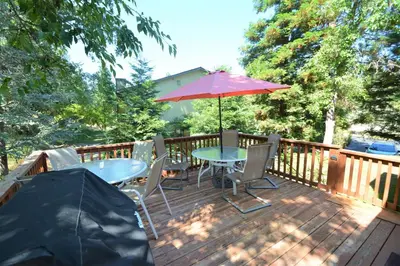 a patio with a table and an umbrella on a deck at Brummett Lodge Winter Special Ends 51226 in Bass Lake