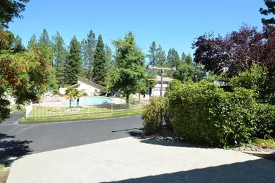 a parking lot with a swimming pool and trees at Brummett Lodge Winter Special Ends 51226 in Bass Lake