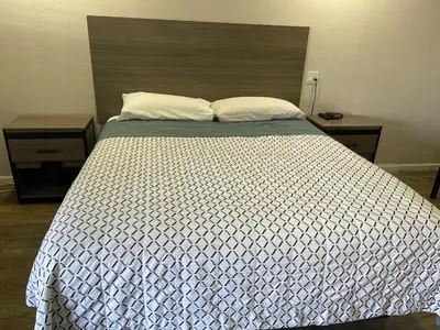 a bedroom with a bed with a white comforter and two tables at Town House Motel in Sanger
