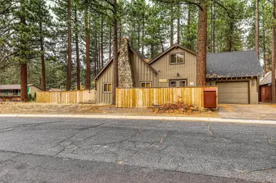 a house with a wooden fence in front of trees at Black Bear Hideaway in South Lake Tahoe