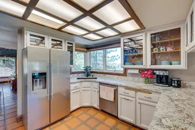 a kitchen with a stainless steel refrigerator and windows at Meadow Vista Mountain Escape with River Views! in Meadow Vista