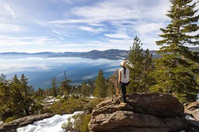 a person standing on top of a rock looking at the water at Agate Bay 3BDR, Walking Distance to the Beach! in Tahoe Vista
