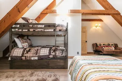 a attic bedroom with two bunk beds and a couch at Brand New 3BDR Cabin 4 Min to Ski Resort and Beach in Tahoma