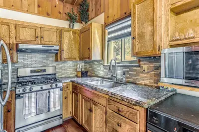 a kitchen with wooden cabinets and a stainless steel sink at 3 Mi to Shaver Lake Cozy Bears Hideaway Cabin! in Shaver Lake