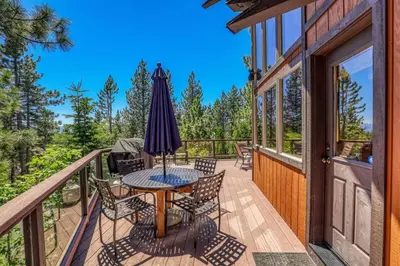 a deck with a table and chairs and an umbrella at EJ's Point Walk to Beach in Tahoe City