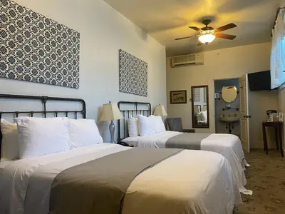 a hotel room with two beds and a ceiling fan at Hotel Sutter in Sutter Creek