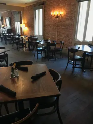 a dining room with tables and chairs and windows at Hotel Sutter in Sutter Creek