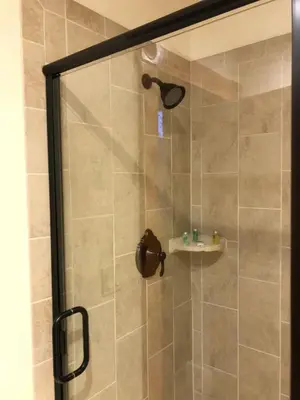 a shower with a glass door next to a sink at Hotel Sutter in Sutter Creek