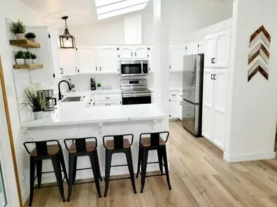 a kitchen with white cabinets and a kitchen island with bar stools at Oasis Riverfront House -10 min to Sequoia in Three Rivers