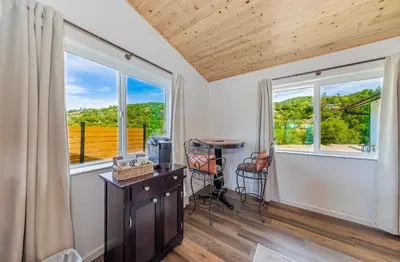 a room with two windows and a desk with a table at Hidden Falls Retreat Peaceful Guesthouse Near Yosemite in Oakhurst