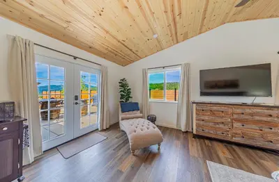 a living room with a television and a wooden ceiling at Hidden Falls Retreat Peaceful Guesthouse Near Yosemite in Oakhurst