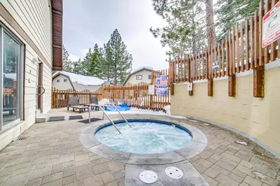 a hot tub in a patio with a fence at Mammoth Lakes Condo with Fireplace and Mountain Views in Mammoth Lakes