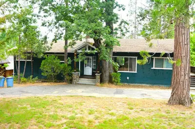 a green house with a tree in front of it at Johnson Lake FrontReduced Nightly Rates in Bass Lake