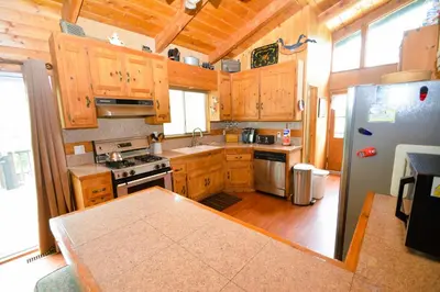 a kitchen with wooden cabinets and a stainless steel refrigerator at Johnson Lake FrontReduced Nightly Rates in Bass Lake