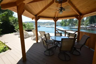 a wooden deck with a table and chairs on the water at Johnson Lake FrontReduced Nightly Rates in Bass Lake