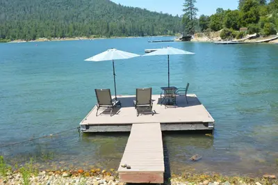 two chairs and umbrellas on a dock on a lake at Lake Shore Lake Front Free Night Special in Bass Lake