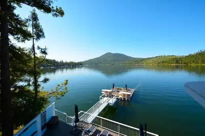 a boat is docked at a dock on a lake at Beautiful Lakefront Home Spectacular View - Herrera in Bass Lake