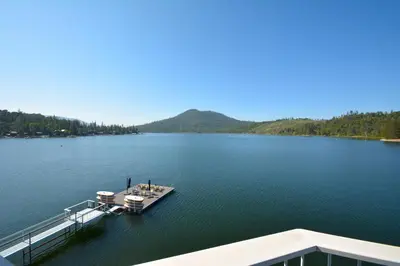 a boat is docked at a dock on a lake at Beautiful Lakefront Home Spectacular View - Herrera in Bass Lake