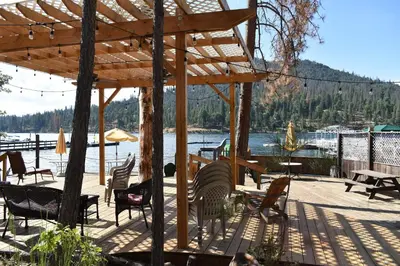 a deck with chairs and tables and a wooden pavilion at Charming 1927 Lake Front Home - Hargrave in Bass Lake