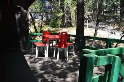 three red chairs and a red table on a porch at Charming 1927 Lake Front Home - Hargrave in Bass Lake