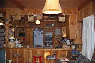 a kitchen with wooden walls and a counter with a refrigerator at Charming 1927 Lake Front Home - Hargrave in Bass Lake