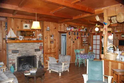 a living room with a fireplace and wooden walls at Charming 1927 Lake Front Home - Hargrave in Bass Lake