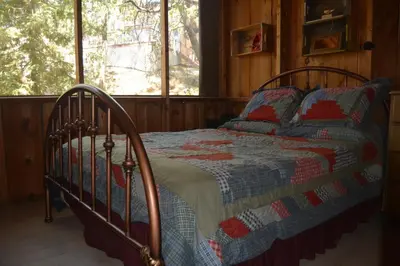 a bedroom with a bed with a quilt on it at Charming 1927 Lake Front Home - Hargrave in Bass Lake