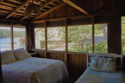 a bedroom with a bed and a window at Charming 1927 Lake Front Home - Hargrave in Bass Lake