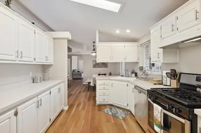 a kitchen with white cabinets and wooden floors at Newly Renovated Retreat on 6 Acres, Discover Murphys Lodge with Scenic Views! in Murphys
