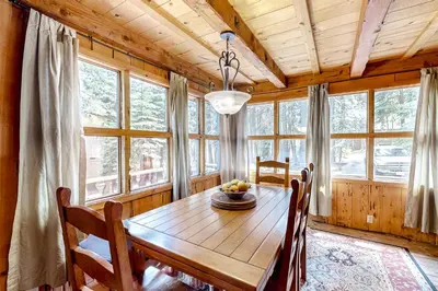 a dining room with a wooden table and some windows at Pine Knolls in Tahoma