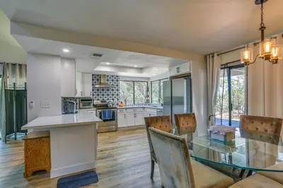 a kitchen and dining room with a glass table and chairs at Pet-Friendly Coarsegold Vacation Rental with Deck! in Coarsegold