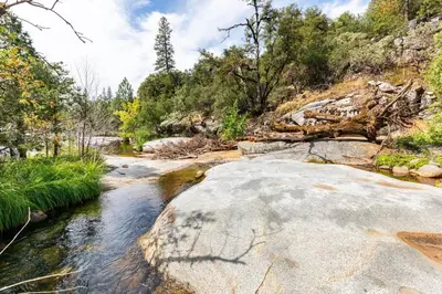 a river with rocks and trees in the background at Ponderosa Creekside Retreat in Mariposa