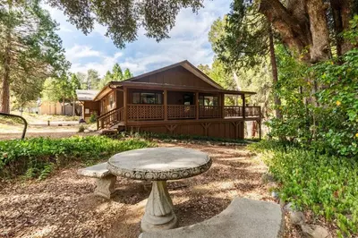 a log cabin with a bench in front of it at Ponderosa Creekside Retreat in Mariposa